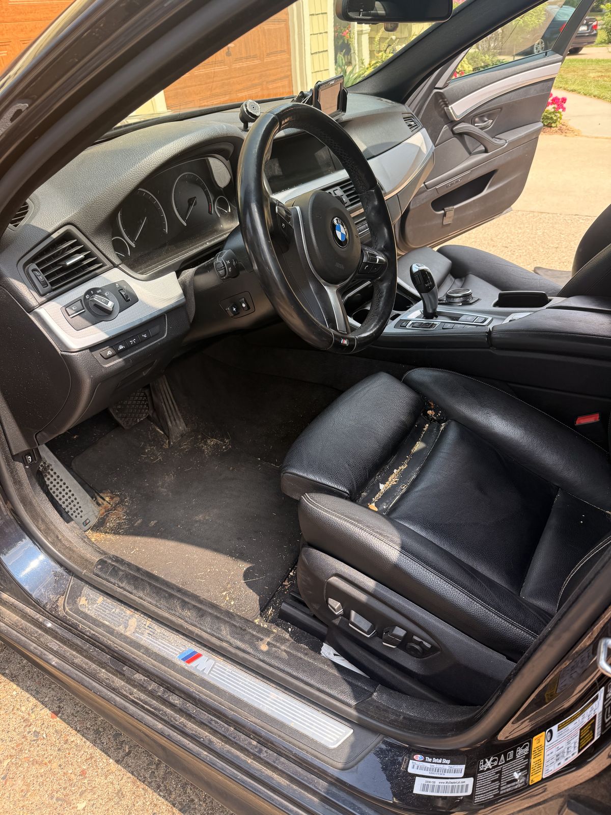 BMW driver's seat and carpet before detail, dust and debris visible