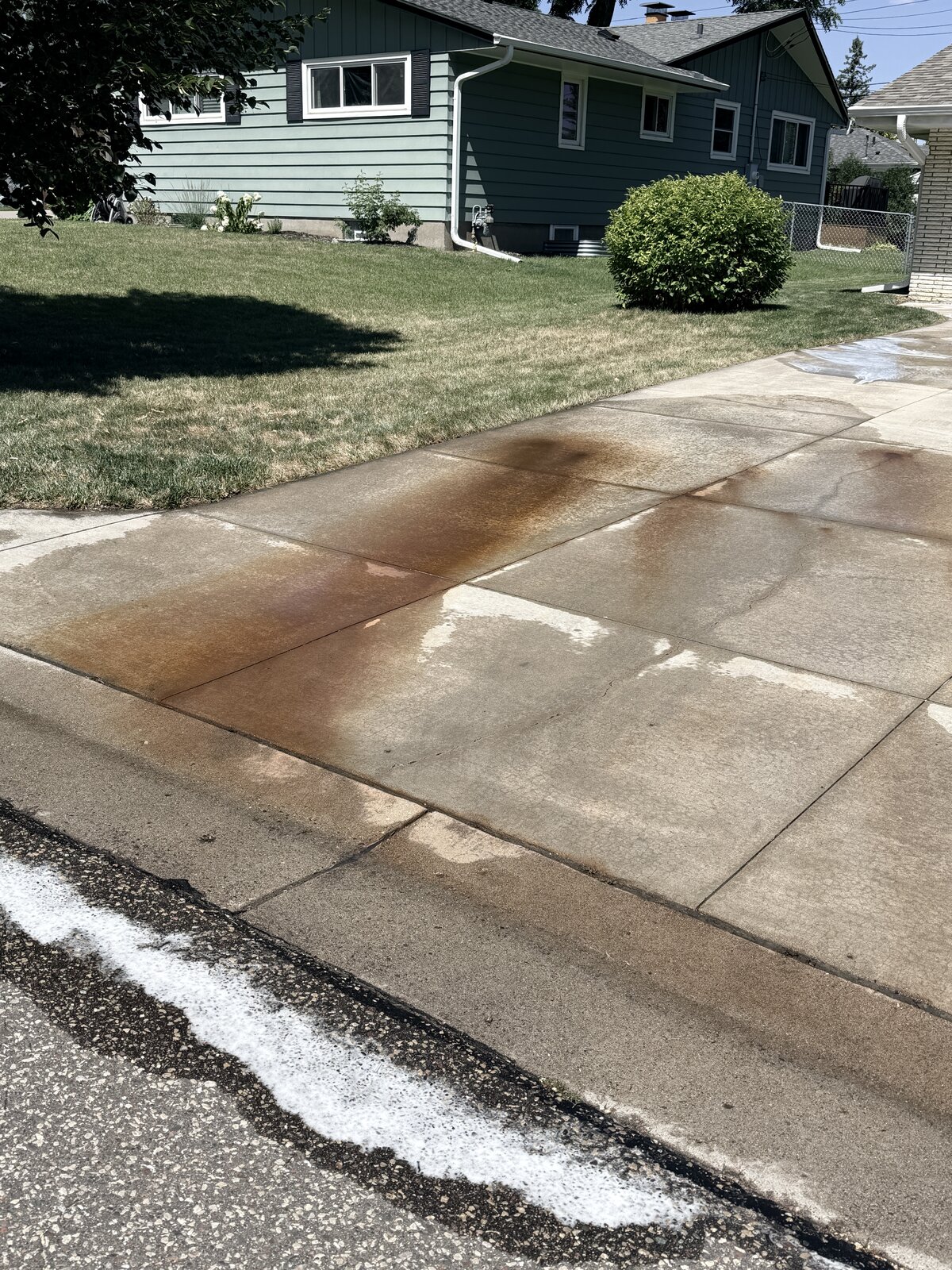 Commercial driveway with severe rust staining bled into the concrete before treatment