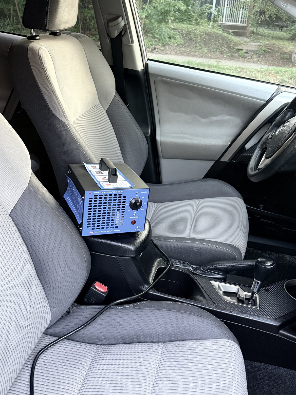 Portable ozone generator running an odor-treatment cycle inside a car interior