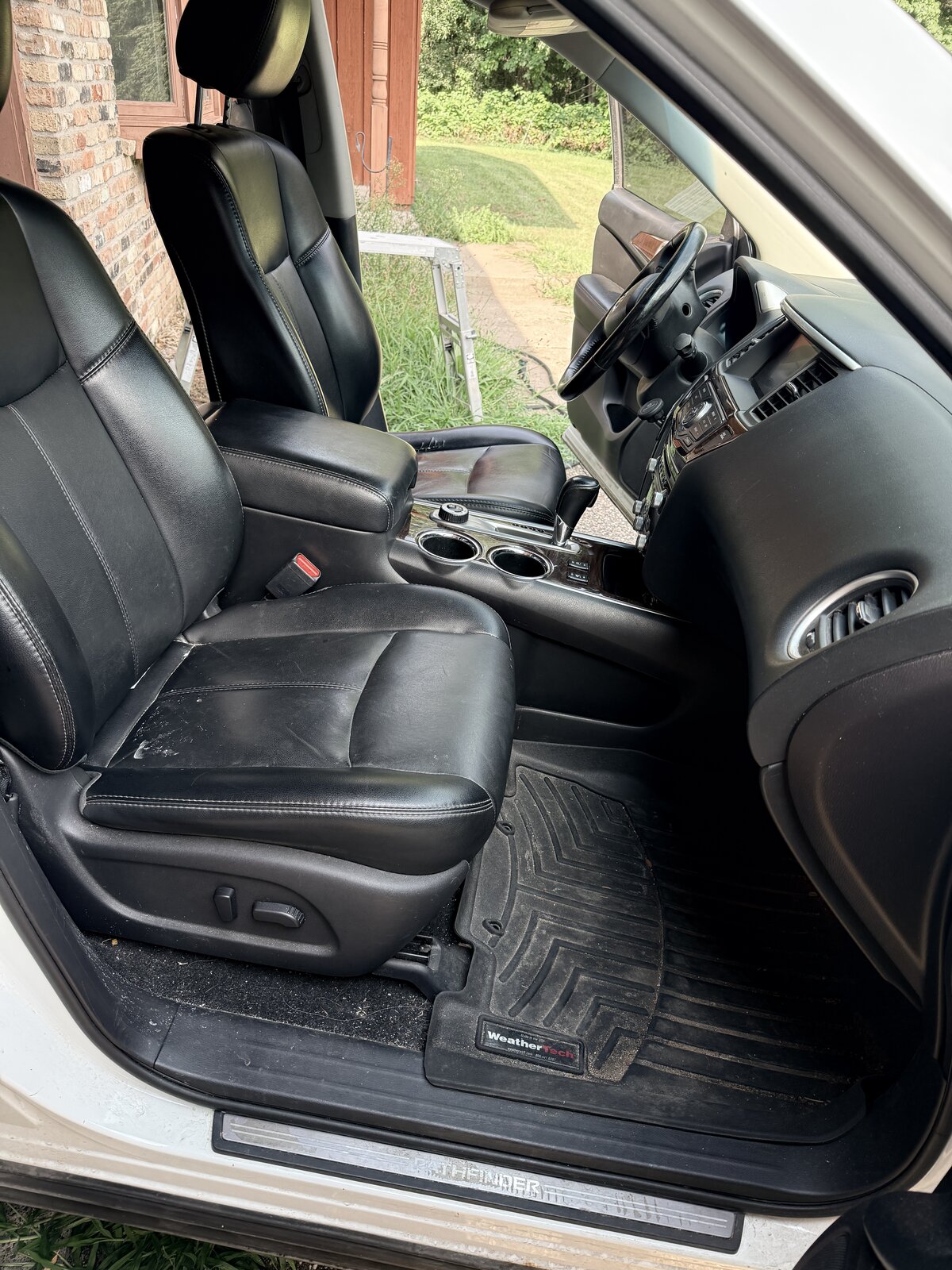 Nissan Pathfinder driver's seat and floor mat before detail, dusty and worn from daily work use